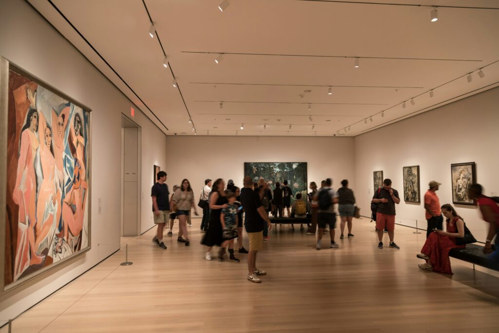 “Visitors walking through a spacious modern art gallery filled with paintings and exhibition lighting.”
Photo by
Bernd 📷 Dittrich on Unspash
https://unsplash.com/photos/a-group-of-people-standing-in-a-museum-looking-at-paintings-3pgOhgQBYoM