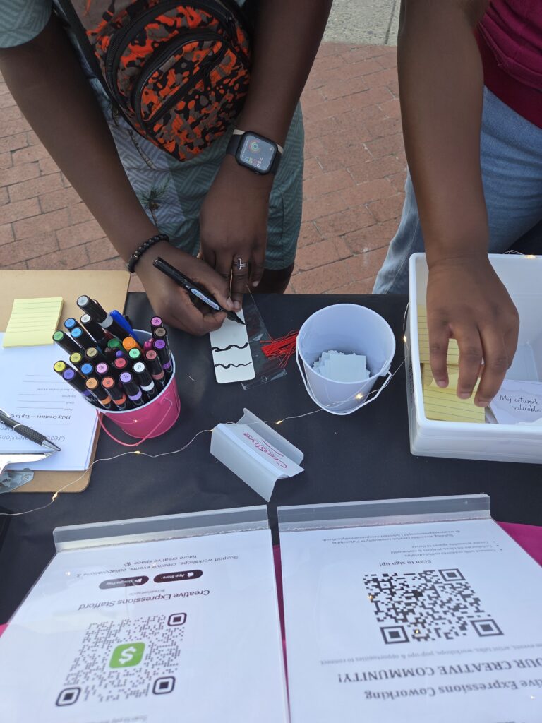 Community members creating affirmation tags and participating in an interactive activity at a Creative Expressions event in Philadelphia.